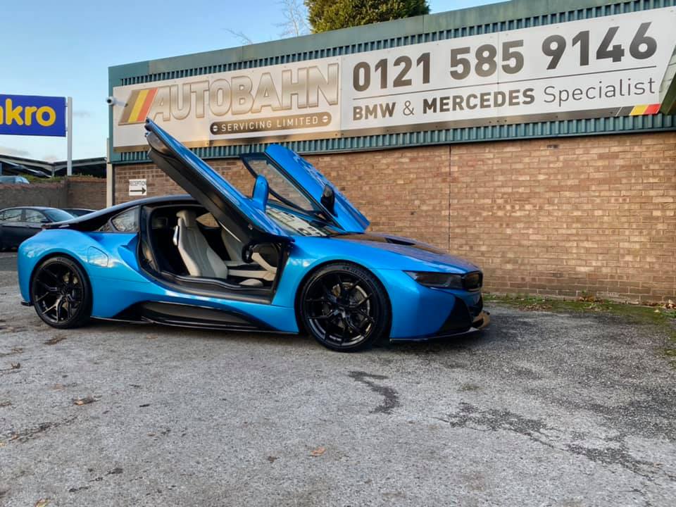 autobahn specialists - blue super car parked under autobahn signage